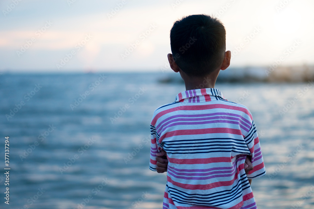 Abstract and blur of asian boy stands back to look at the sea in the evening. Abstract and blur of asian boy stands back to look at the sea in the evening.