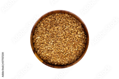 Brown dried uncooked buckwheat flakes in round wooden bowl isolated on white background.
