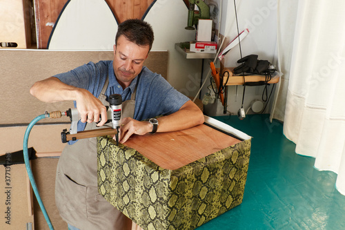 Qualified workman upholstering furniture in repair furniture