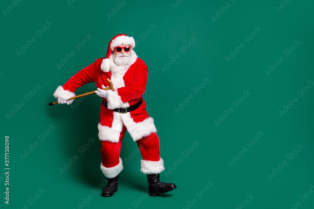 Full length body size view of his he nice attractive handsome cheery Santa holding in hand cane having fun dancing rest celebratory festive day occasion isolated over green color background Full length body size view of his he nice attractive handsome cheery Santa holding in hand cane having fun dancing rest celebratory festive day occasion isolated over green color background
