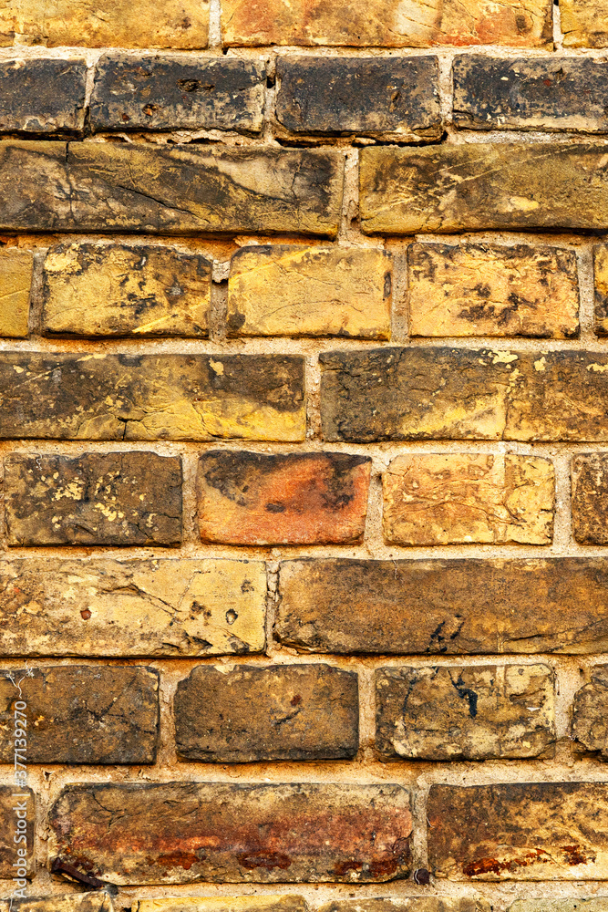 Fototapeta premium vintage brick wall in yellow. yellow brick wall texture for background, vertical image..
