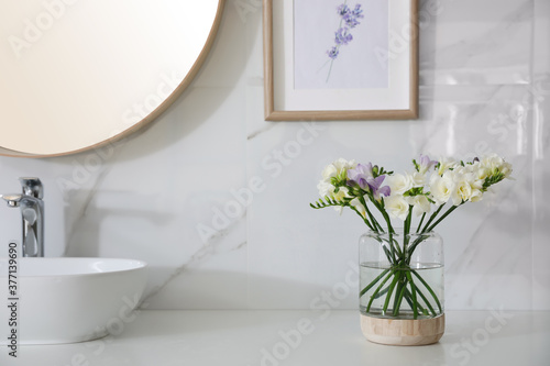 Beautiful freesia flowers on countertop in bathroom