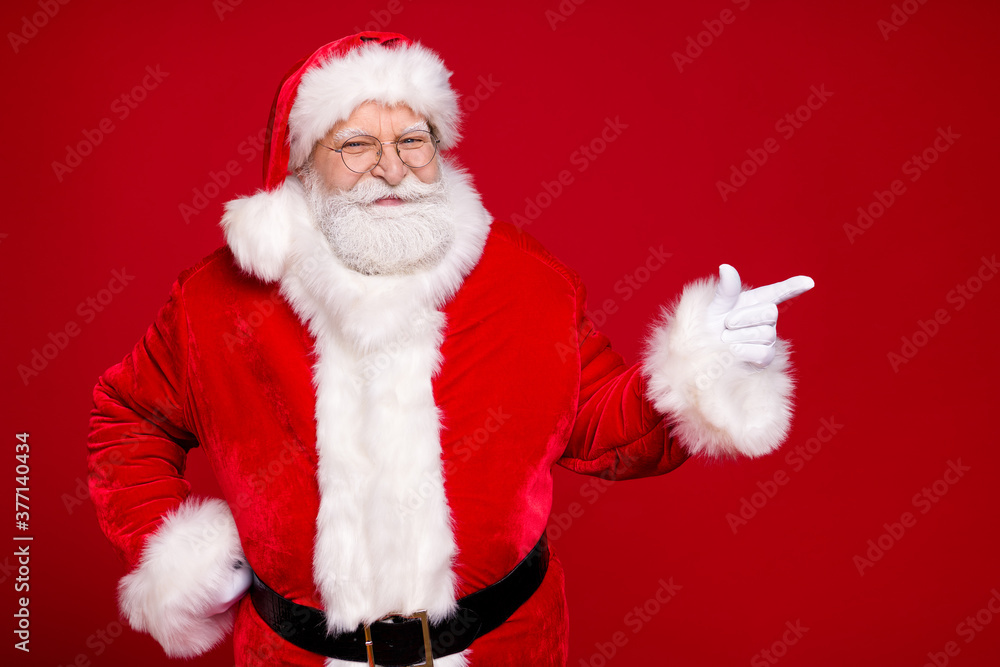 Photo of retired old man grey beard hand hip direct finger empty space propose newyear decor wear santa costume leather belt gloves coat spectacles headwear isolated red color background Photo of retired old man grey beard hand hip direct finger empty space propose newyear decor wear santa costume leather belt gloves coat spectacles headwear isolated red color background