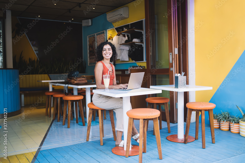 Portrait of cheerful IT professional with sincerely smile laughing at camera during remote working in cafe with good internet connection, successful female freelancer posing at table with netbook Portrait of cheerful IT professional with sincerely smile laughing at camera during remote working in cafe with good internet connection, successful female freelancer posing at table with netbook