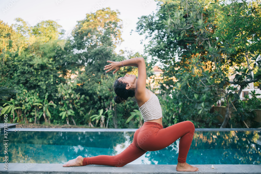 Strong female in active wear standing in Andjanasana enjoying harmony  practice and balance exercising, calm woman feeling body flexibility during  morning yoga training at pool terrace in porch Stock Photo | Adobe