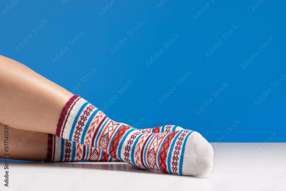 Close up of colorful soft socks on female legs. Space for design on blue background. Close up of colorful soft socks on female legs. Space for design on blue background.