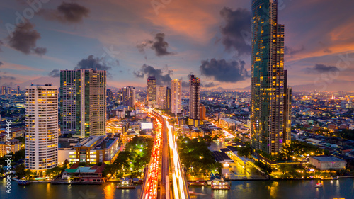 Aerial view of Taksin Bridge with Chao Phraya River, Bangkok Downtown, Thailand, Financial district and business center skylind and skyscaper urban city and high-rise buildings at night. © Kalyakan