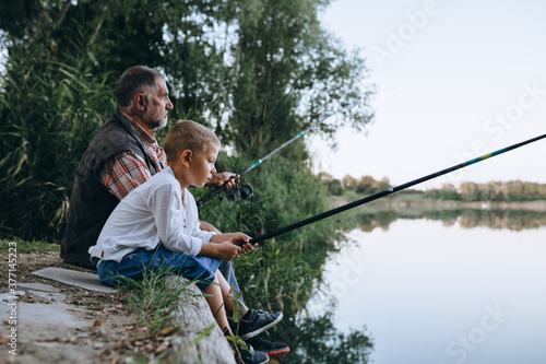 grandfather with his grandson fishing outdoor on the lake
