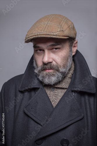 Close up portrait of 50-year-old man wearing coat and hat. Copy-space. Studio shot