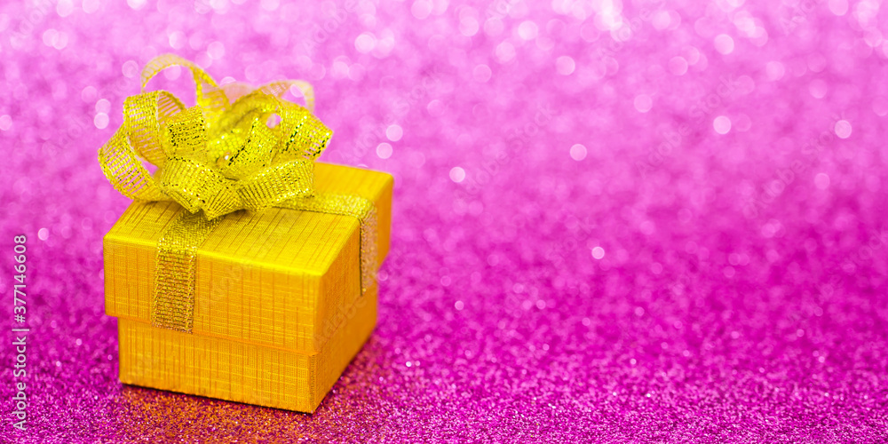 Gold gift box with pink bokeh background. Holiday greeting card. Christmas, new year, birthday. Space for text Gold gift box with pink bokeh background. Holiday greeting card. Christmas, new year, birthday. Space for text