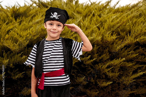 Cute boy in pirate costume standing by bushes photo