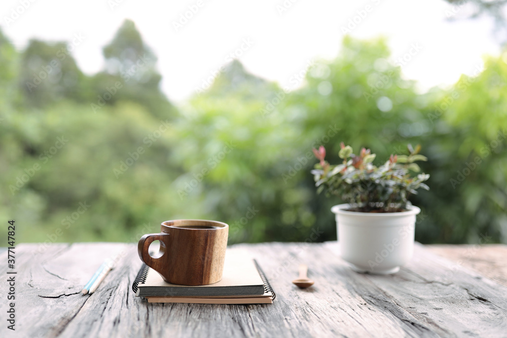 Traditional brown wooden cup with notebooks and white plant pot on wooden table