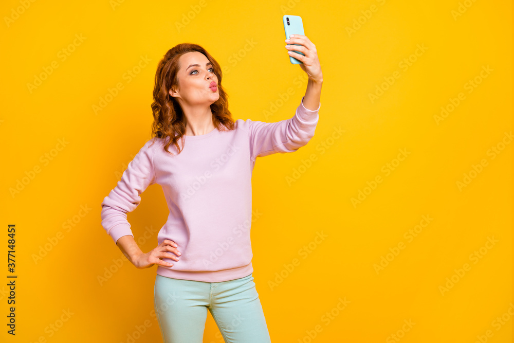 Photo of adorable pretty lady hold telephone hand making selfies boyfriend flirty mood sending air kisses wear pink sweater green pants isolated yellow color background Photo of adorable pretty lady hold telephone hand making selfies boyfriend flirty mood sending air kisses wear pink sweater green pants isolated yellow color background