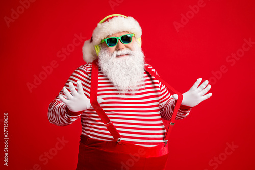 Portrait of his he handsome bearded fat overweight cheery Santa listen single hit sound stereo jazz funk rest chill leisure pulling suspenders isolated bright vivid shine vibrant red color background