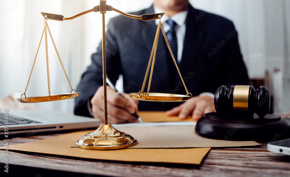 Business and lawyers discussing contract papers with brass scale on desk in office. Law, legal services, advice, justice and law concept picture with film grain effect Business and lawyers discussing contract papers with brass scale on desk in office. Law, legal services, advice, justice and law concept picture with film grain effect