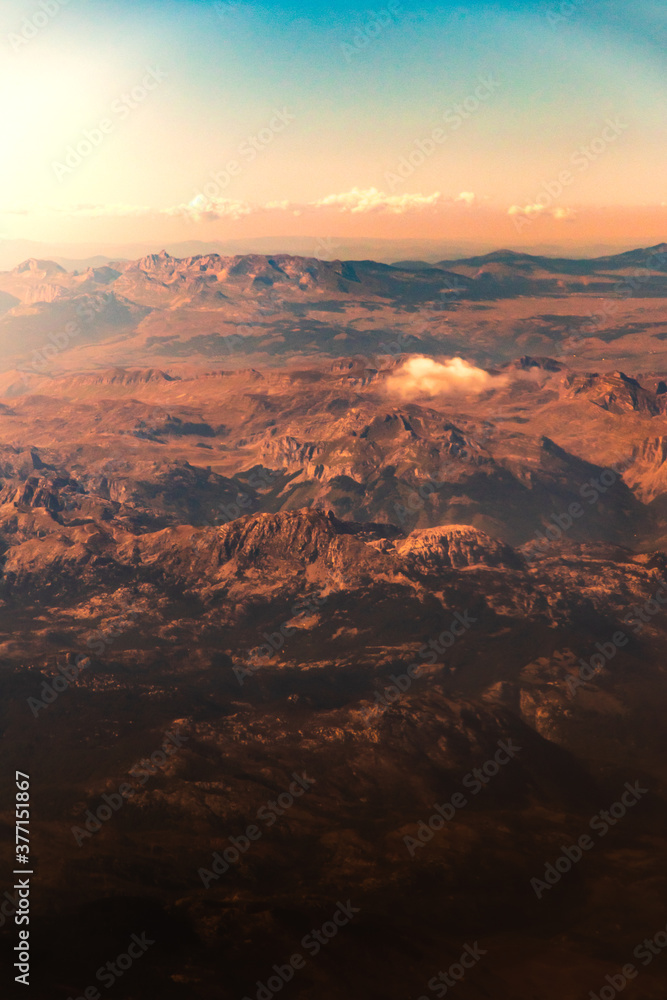 Beautiful atmospheric mountain landscape from the porthole of a flying plane