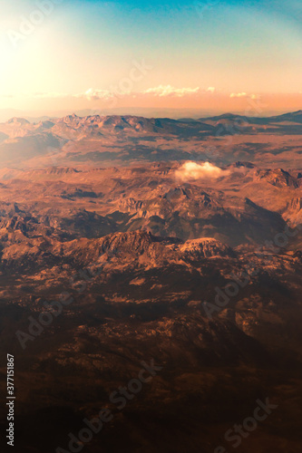 Beautiful atmospheric mountain landscape from the porthole of a flying plane © FellowNeko