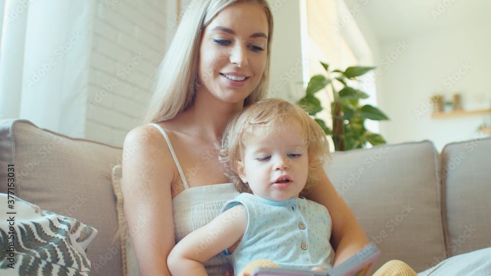 Young beautiful mother playing with baby daughter on sofa at home. Young beautiful mother playing with baby daughter on sofa at home.