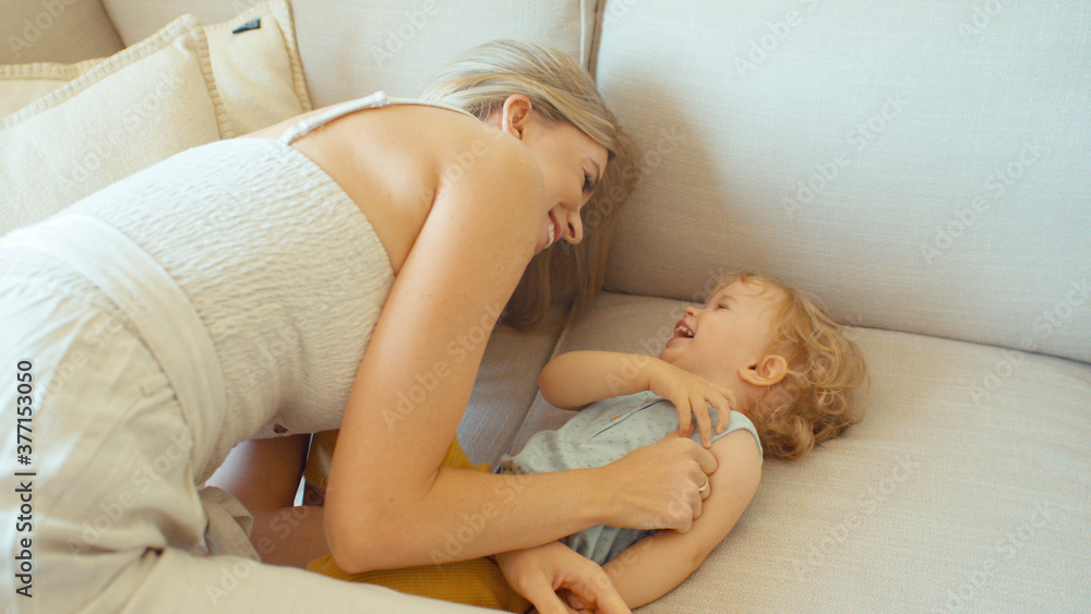 Young beautiful mother playing with baby daughter on sofa at home. Young beautiful mother playing with baby daughter on sofa at home.