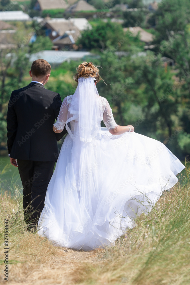 The bride and groom stand back, hold hands. 