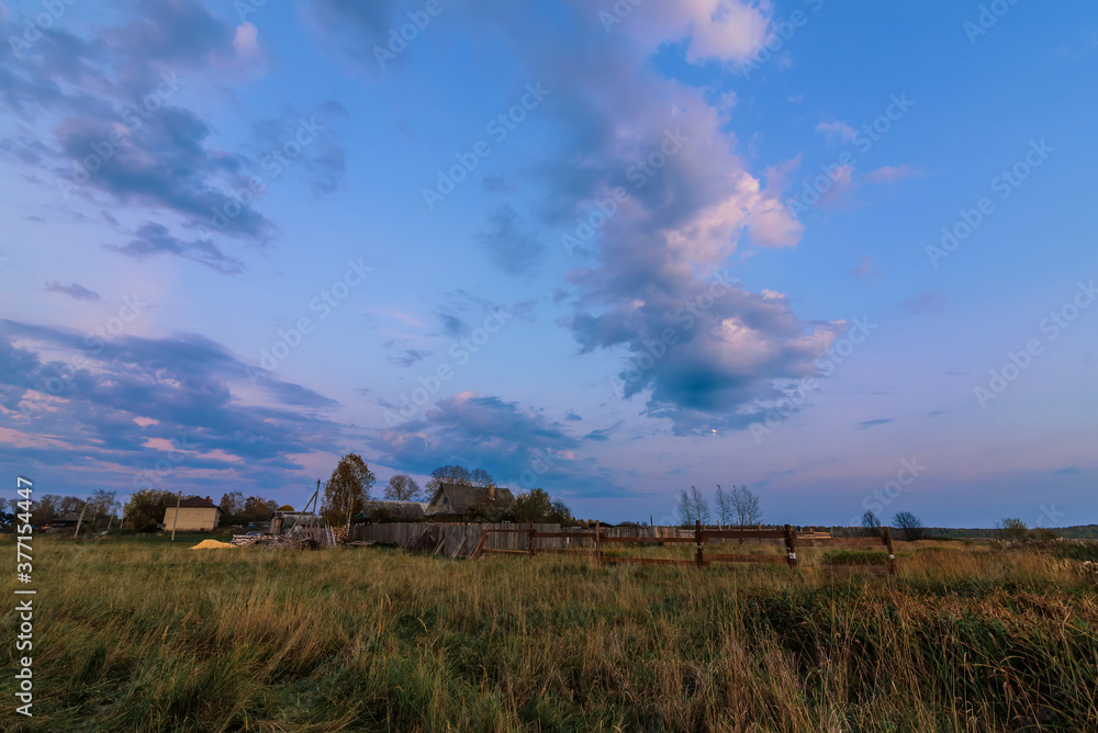 rural landscape with a house in the village in the evening at dusk in autumn