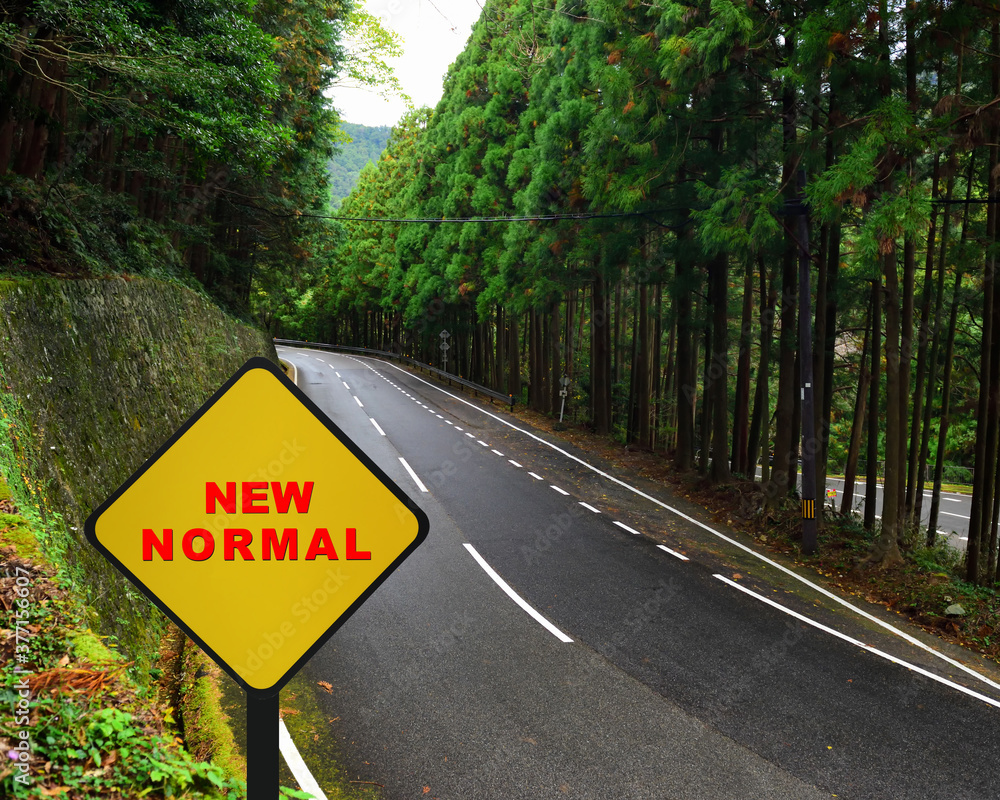 New normal word on yellow sign on highway road mountain background. Coronavirus disease 2019 or Covid-19 disruption concept and natural background idea