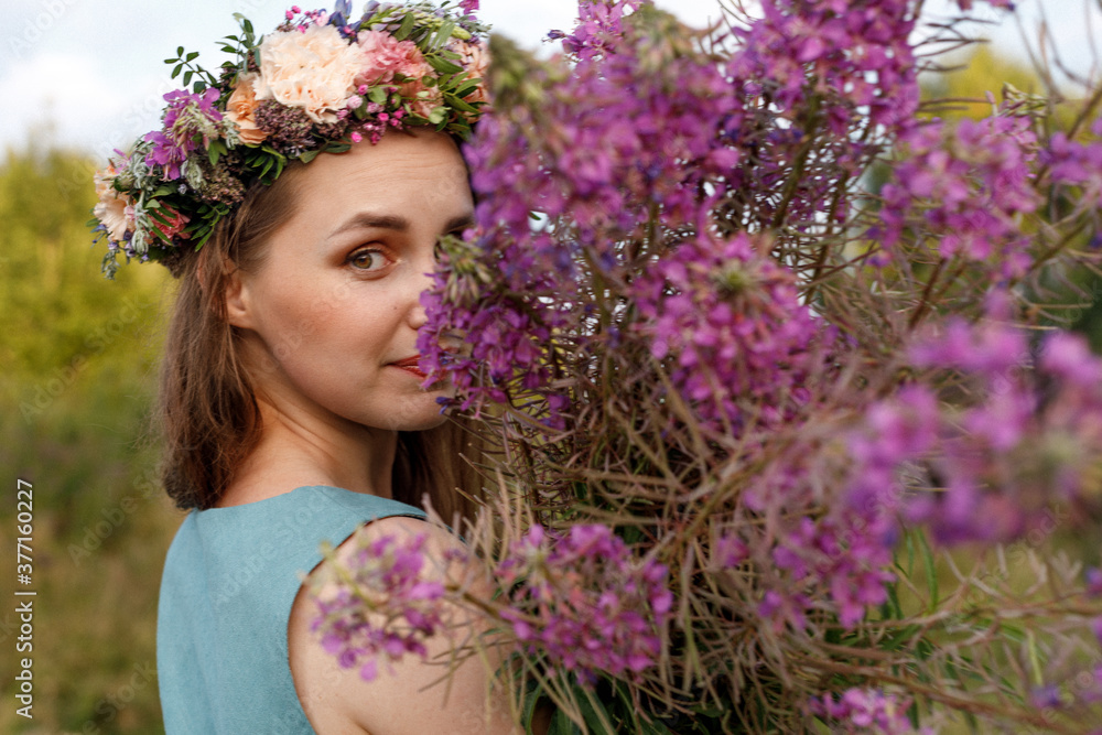 Slavic beauty with a floral wreath on her head and a bouquet of wildflowers. Ancient pagan origin celebration concept. Summer solstice day. Mid summer. Ancient rituals. Slavic beauty with a floral wreath on her head and a bouquet of wildflowers. Ancient pagan origin celebration concept. Summer solstice day. Mid summer. Ancient rituals.