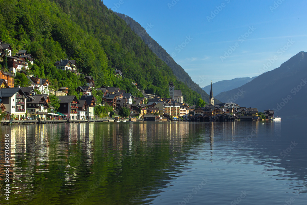 Classic postcard view of famous Hallstatt lakeside town, Austria. Scenic panoramic view of beautiful town reflecting in Hallstatter See.Beautiful sunny day in summer, Salzkammergut region.Urban scene