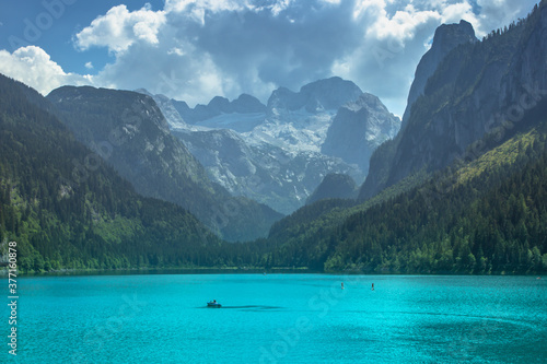 View of majestic mountains and lake.Nature getaway.Turquoise water of Gosau See (lake),Austria,Dachstein glacier in background.Vacation travel scene.Alpine lake surrounded by mountains.Paddle boarding © Eva
