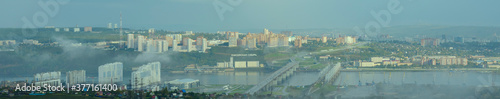 Panorama of city of Krasnoyarsk in Russia at sunrise. Yenisei River, fog. Nikolaevsky bridge connect  Oktyabrsky and Sverdlovsky districts of Krasnoyarsk. Text in Russian 