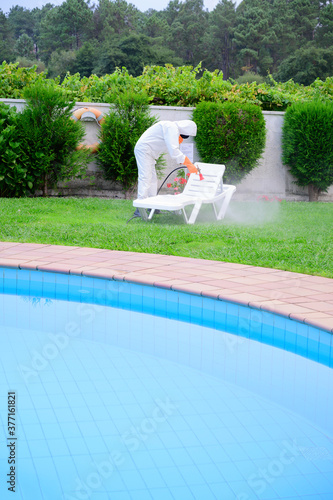 man with protection against covid 19 disinfects the pool garden by spraying with disinfectant product and spraying product
