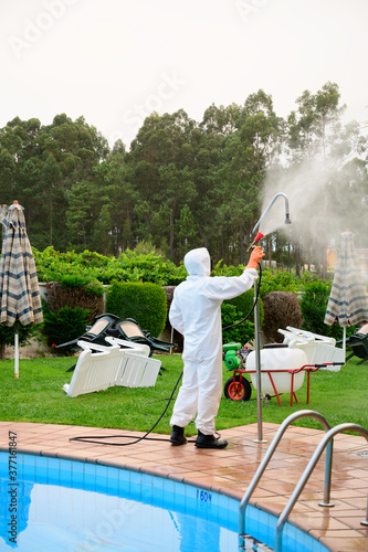 man with protection against covid 19 disinfects the pool showers by spraying with disinfectant product and spraying product