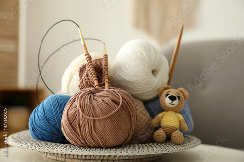 Toy bear, clews with needles and crochet on table. Engaging in hobby photo