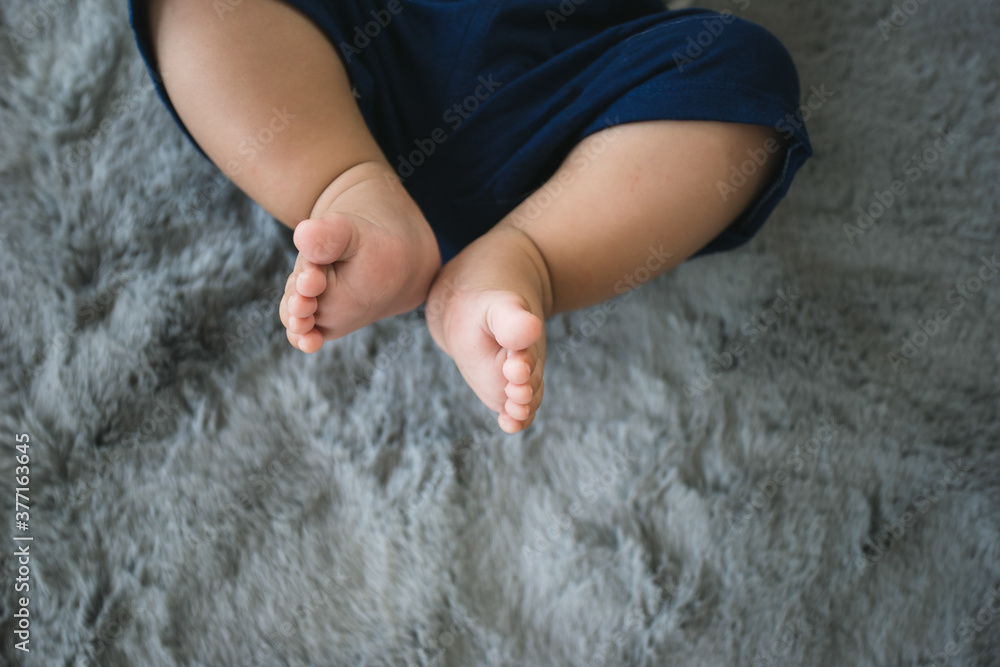 New born baby feet on grey carpet, chubby leg adorable of child. New born baby feet on grey carpet, chubby leg adorable of child.