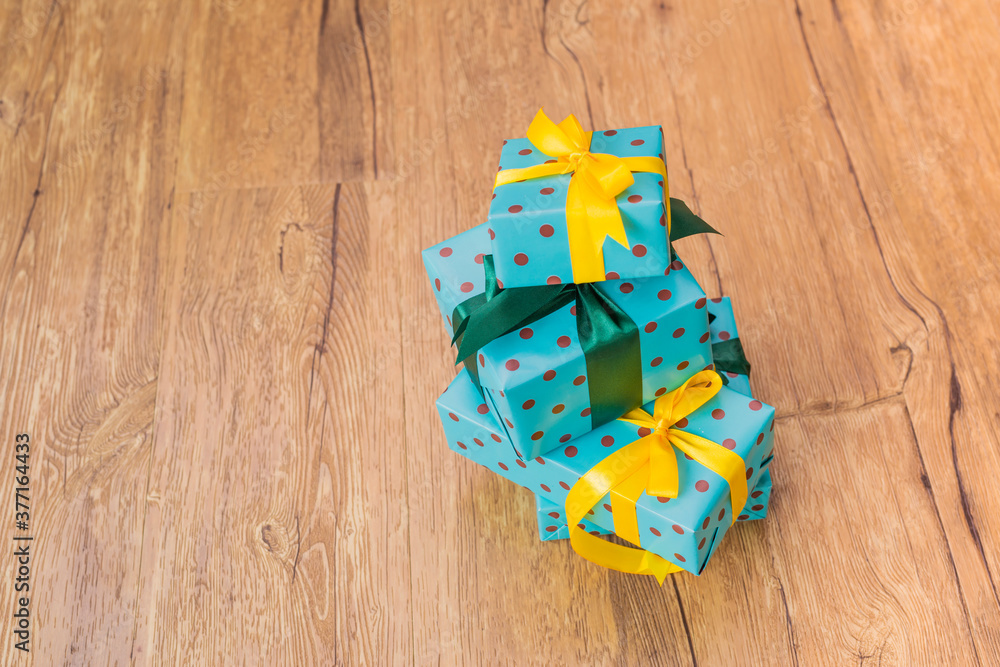 Stack of Blue gift box with dots, yellow and green ribbon with copy space on wood table background. Stack of Blue gift box with dots, yellow and green ribbon with copy space on wood table background.