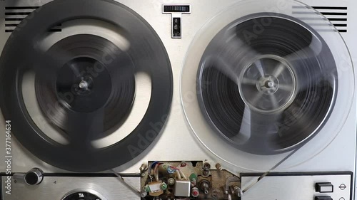 old and vintage bobbin tape recorder rewinding tape close up, top view
