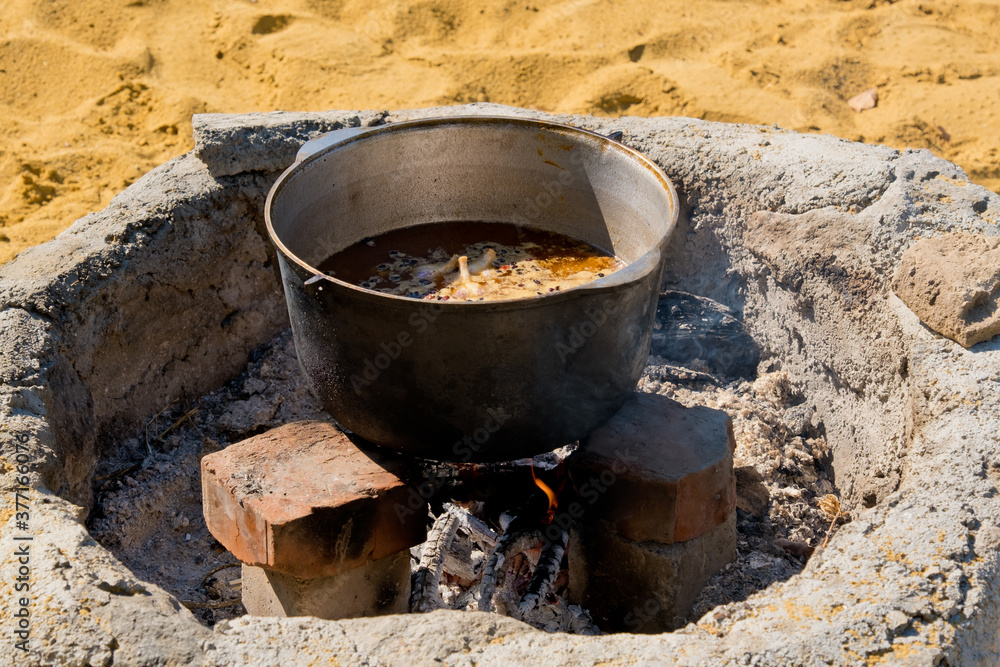 Cooking pilaf in a large cauldron over an open fire. Close-up. Cooking pilaf in a large cauldron over an open fire. Close-up.