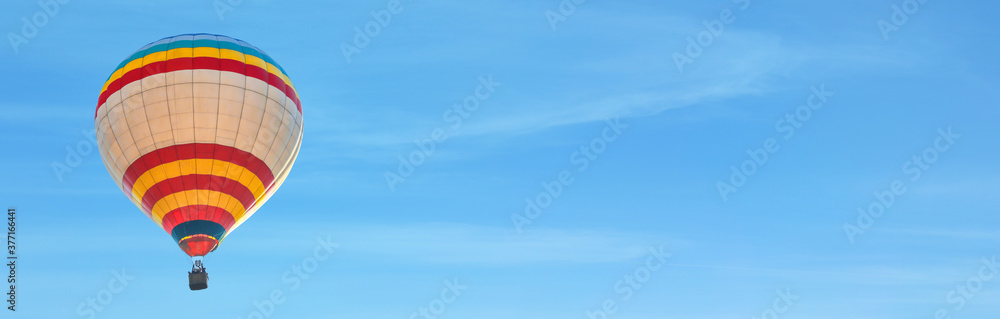 Fototapeta premium Hot air balloon in blue sky, space for text. Banner design