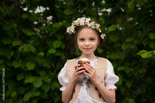 Little smiling girl with easter bread kulich in hand. Kid with Easter cake
