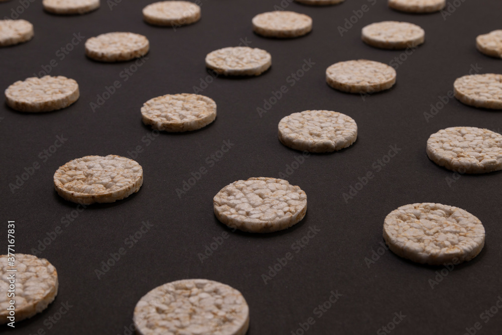 Pattern distribution of rice crackers. Round rice crackers, spread out on a black background. Front or perspective design. Low key photography. Pattern distribution of rice crackers. Round rice crackers, spread out on a black background. Front or perspective design. Low key photography.
