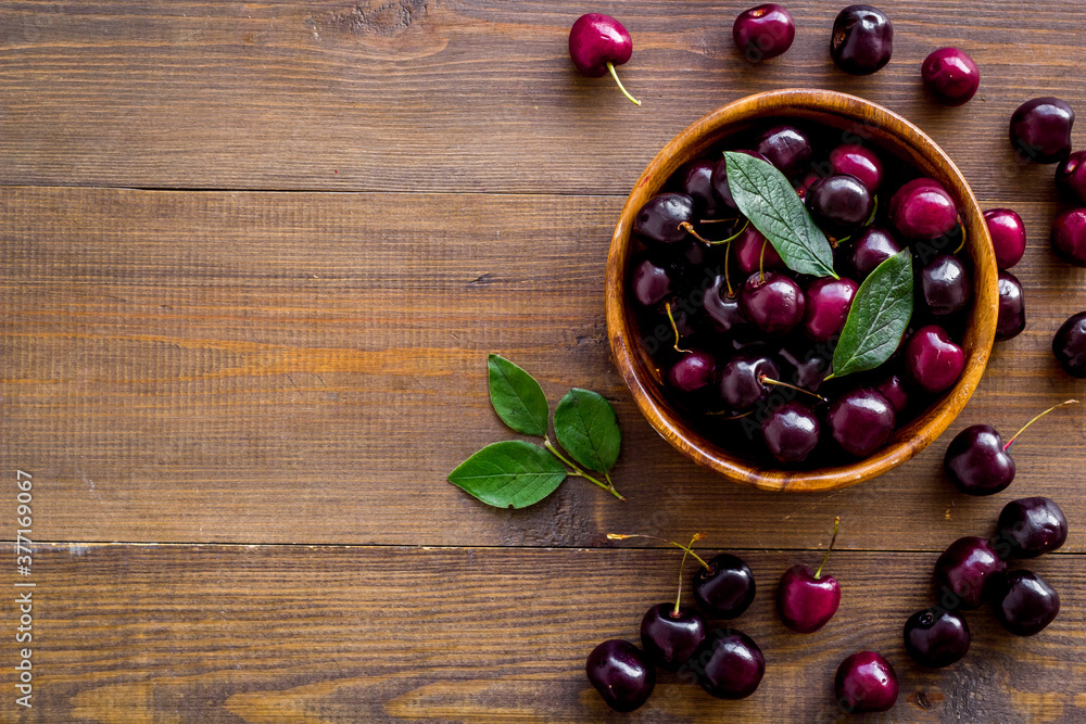 Red cherries with leaves in wooden bowl. Layout, berries background Red cherries with leaves in wooden bowl. Layout, berries background