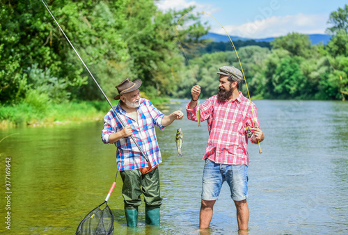 magnificent moments. male friendship. family bonding. two fishermen with fishing rods. summer weekend. mature men fisher. hobby and sport activity. Trout bait. father and son fishing