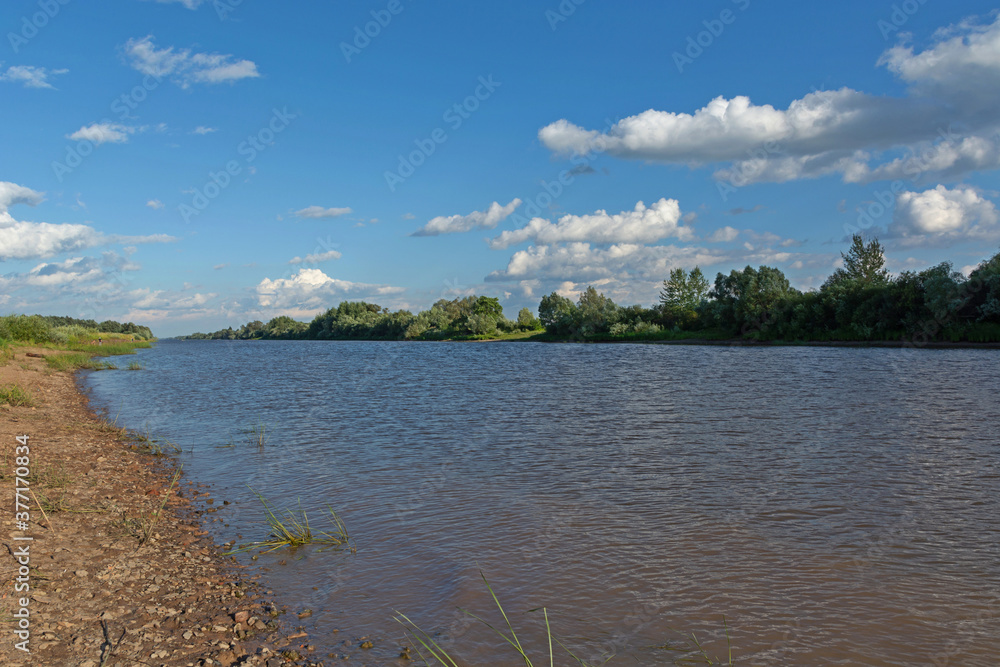 Summer landscape of a European river against a blue cloudy sky.Maly Volkhovets River.Novgorod region