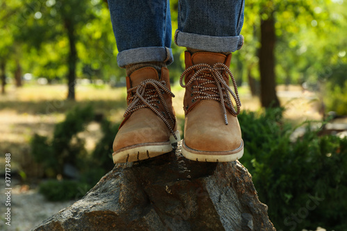 Woman in jeans and boots standing on rock outdoor, close up