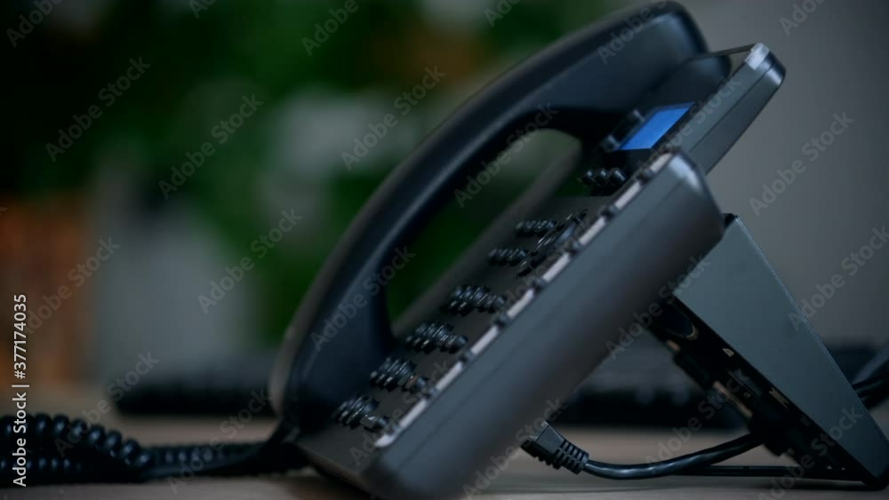 Office worker uses a landline phone to answer incoming calls and dialing a number to make a call. Close-up of women's hands with a phone Office worker uses a landline phone to answer incoming calls and dialing a number to make a call. Close-up of women's hands with a phone