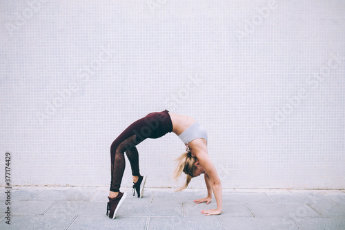 Strong sportswoman practicing yoga on street