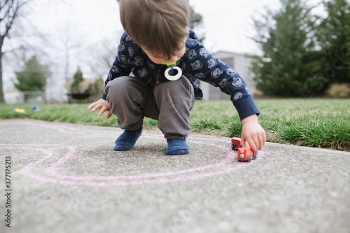 boy plays with trains on sidewalk photo