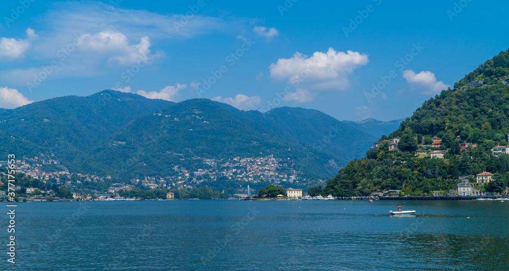 Boat with fisherman on Lake Como, Italy with traditional houses in the hill