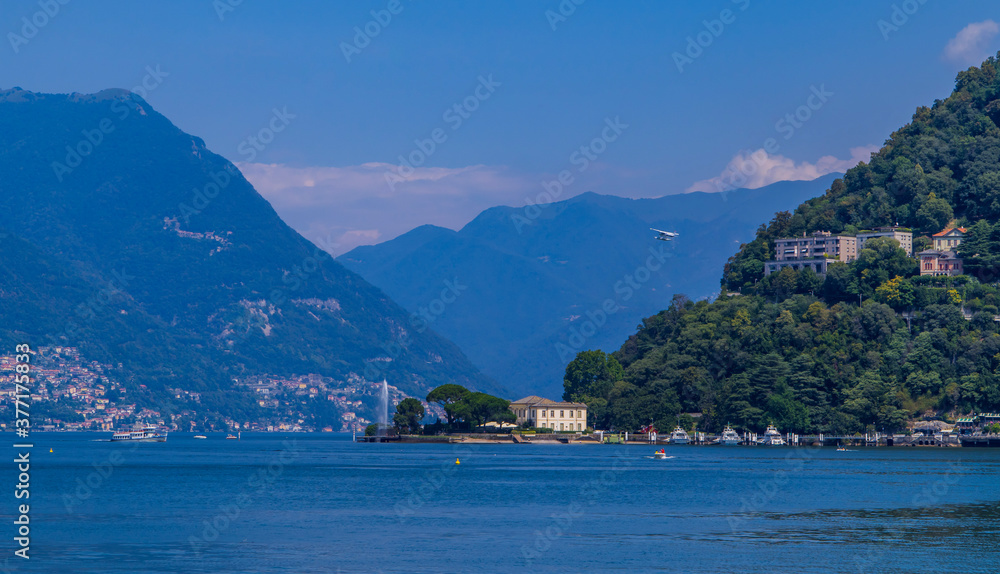 Panoramic view of Lake Como, Italy with water plane flying, fountain, boats, and towns