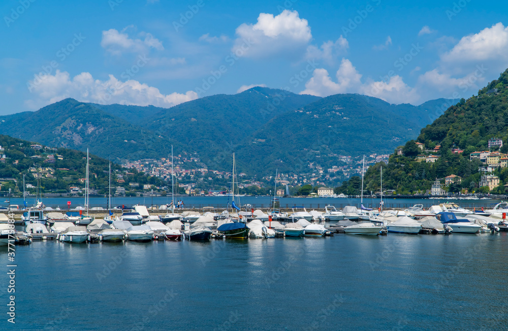 Sailing boats and leisure motor boats on Lake Como, Italy between mountains